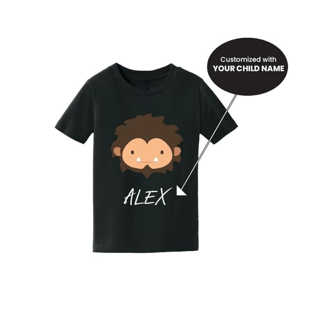 A black kids' t-shirt featuring a cute cartoon Sasquatch face and customizable text for a child's name.