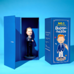 Open blue box reveals a man in a dark suit bobblehead standing on a round base inside.