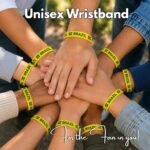 Group of diverse hands stacked together, each wearing yellow Brazil wristbands; caption reads 'Unisex Wristband' and 'For the Fan in you!'