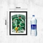 Framed Saudi Arabia football poster with a player kicking a ball; dimensions 30 cm by 40 cm, beside a 1 L water bottle for scale.