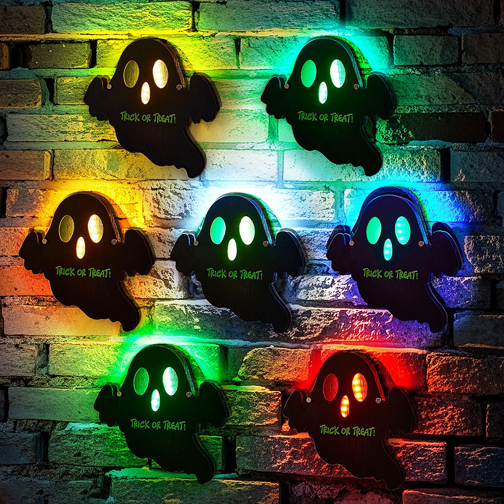Six black ghost Halloween cutouts with multicolored LED backlights on a brick wall, each saying 'Trick or Treat'.